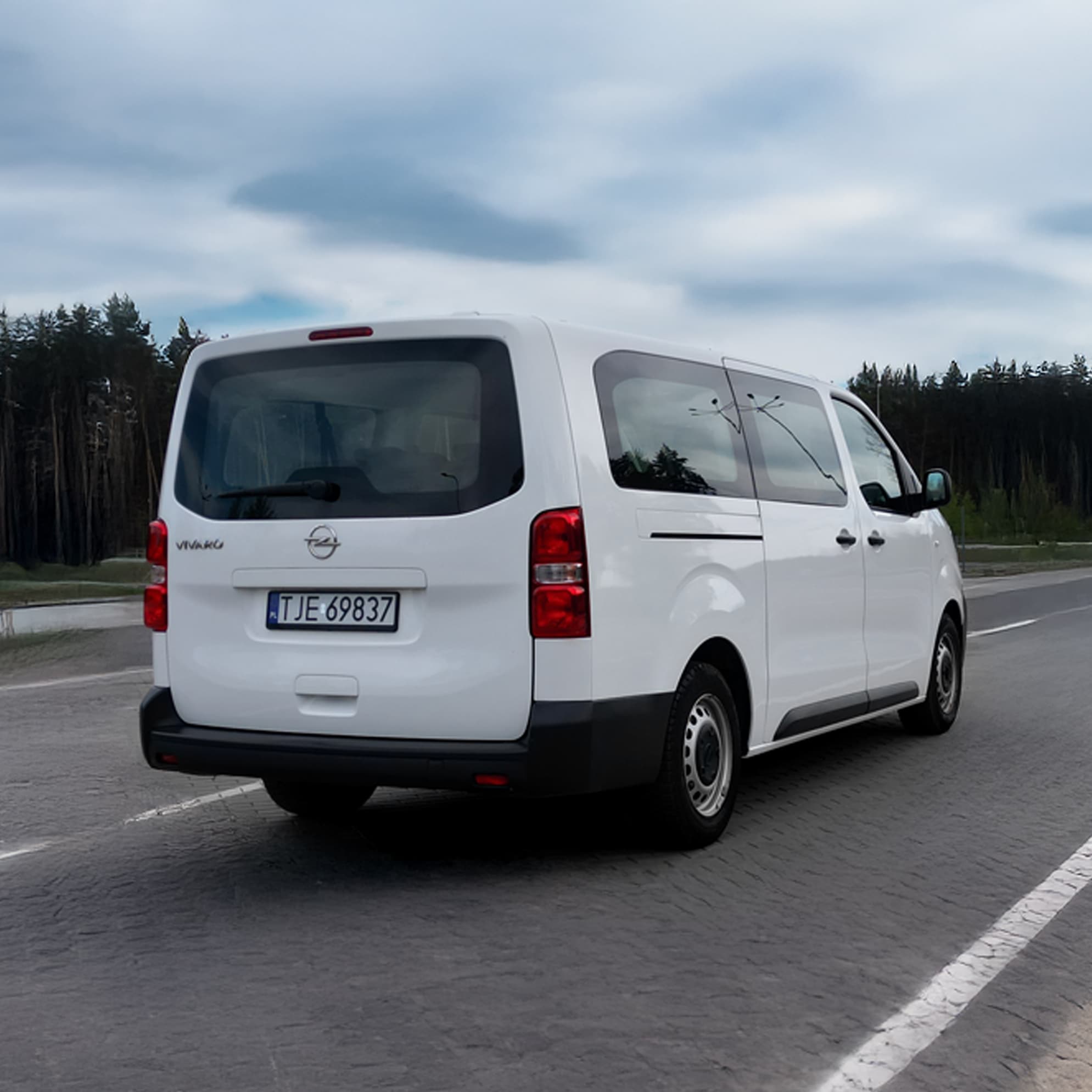 Biały bus 9-osobowy - zdjęcie z tyłu, na drodze